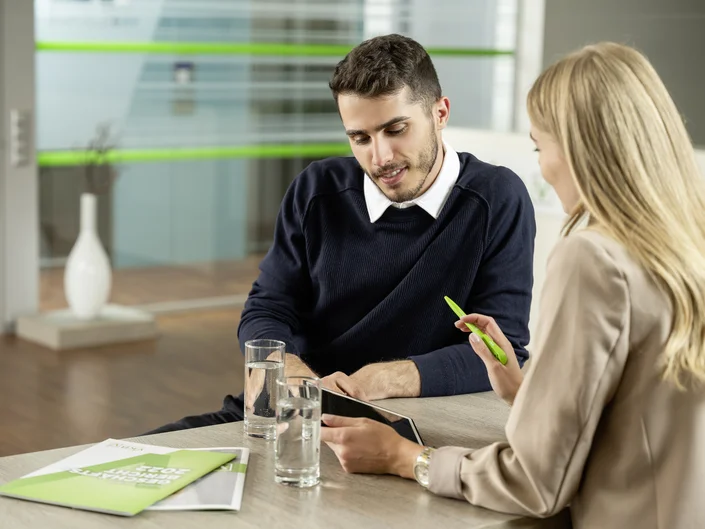 Zwei Personen im Beratungsgespräch an einem Tisch einer VKB-Filiale